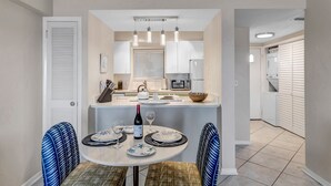 Una cocina moderna con armarios blancos, una isla central y lámparas colgantes.