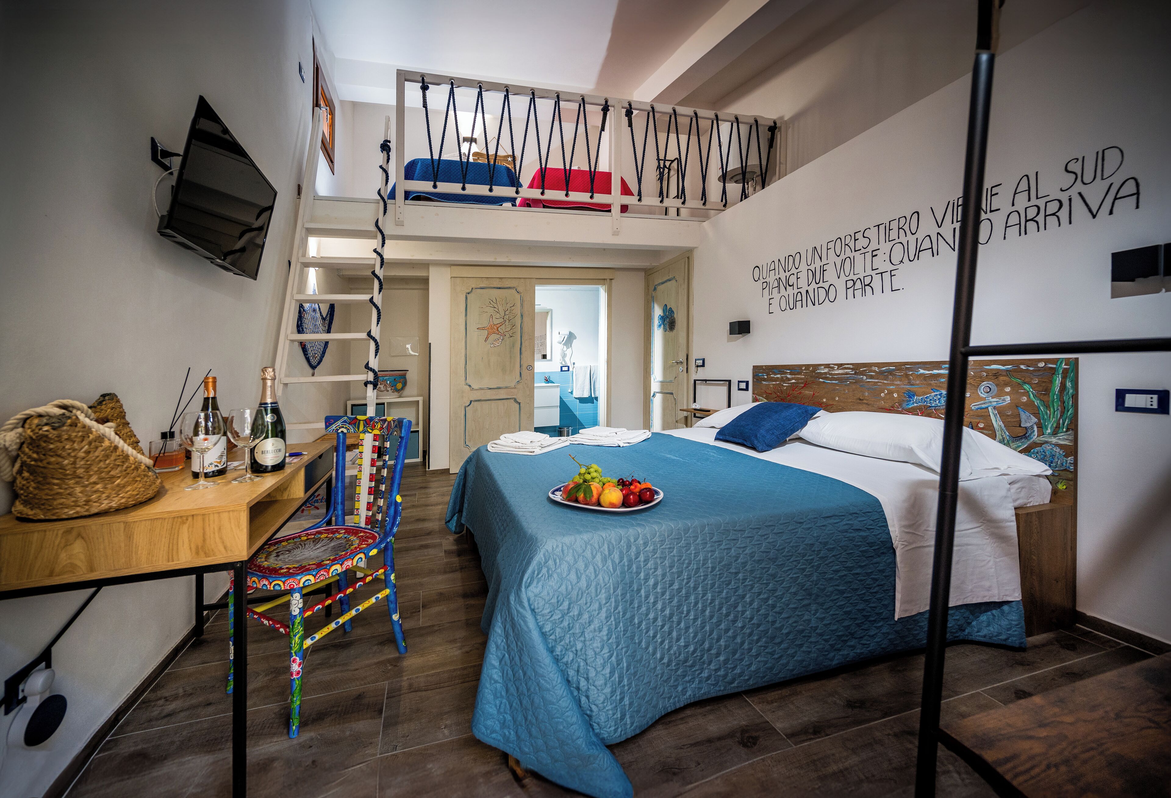 A bedroom with a bed, a desk, a chair, a TV, and a balcony.