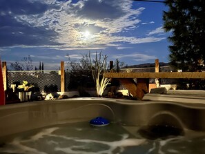 A hot tub with a wooden deck and a metal fence in the background. - Ohana Ranch: Family fun! Themed bedrooms, hot tub, cowboy pool, near JT Park (Yucca Valley)