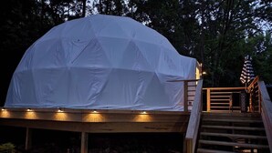 A dome-shaped tent with a wooden deck and steps leading up to it.