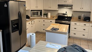 A modern kitchen with white cabinets, stainless steel appliances, and a wooden island. - Tupelo house near mall (Saltillo)