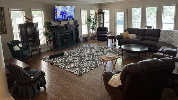 A spacious living room with a fireplace, comfortable seating, a television, and large windows. - Tupelo house near mall (Saltillo)