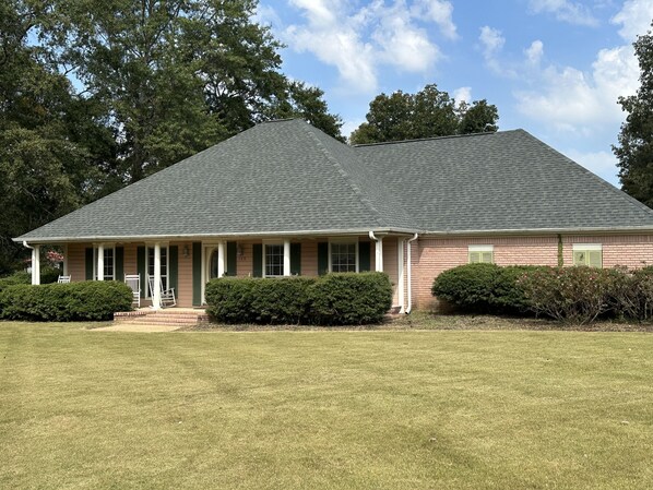 A two-story house with a gabled roof, a front porch with white columns, and a brick facade. - Tupelo house near mall (Saltillo)