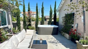 Een terras met een hottub, een bank en potplanten.