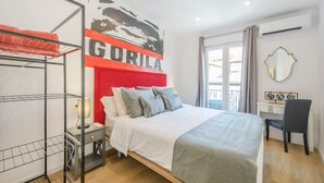 A bedroom with a bed, a desk, a chair, a wardrobe, and a large window. - Top groups MALASAñA, by MoNARO (Centro)