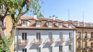 A row of multi-story buildings with balconies, terracotta tiled roofs, and a tree in the foreground. - Top groups MALASAñA, by MoNARO (Centro)