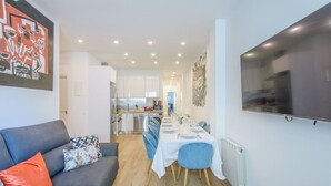 A modern apartment with a living room, dining area, kitchen, and a large TV mounted on the wall. - Top groups MALASAñA, by MoNARO (Centro)