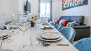 A dining table set with wine glasses, plates, and cutlery in a modern hotel room with a sofa and artwork in the background. - Top groups MALASAñA, by MoNARO (Centro)
