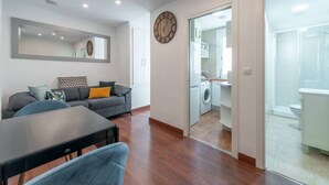 A modern apartment with a dining area, sofa, and a view into the kitchen and bathroom. - Centro Historico MAD. 2BR 1BTH (Madrid)