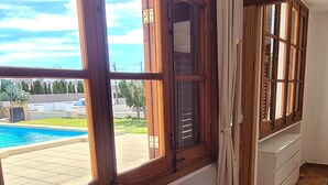 Ein Zimmer mit großen Fenstern, einer Bank und Blick auf einen Swimmingpool.