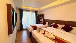 A hotel room with two beds, a TV mounted on the wall, a wooden floor, and a window with curtains. - Hotel Abi International (Kathmandu)