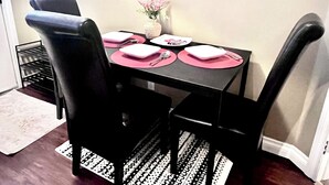 Une table à manger avec quatre chaises, des sets de table roses et un vase rempli de fleurs.