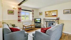 A living room with a fireplace, a television, and a large window with curtains.