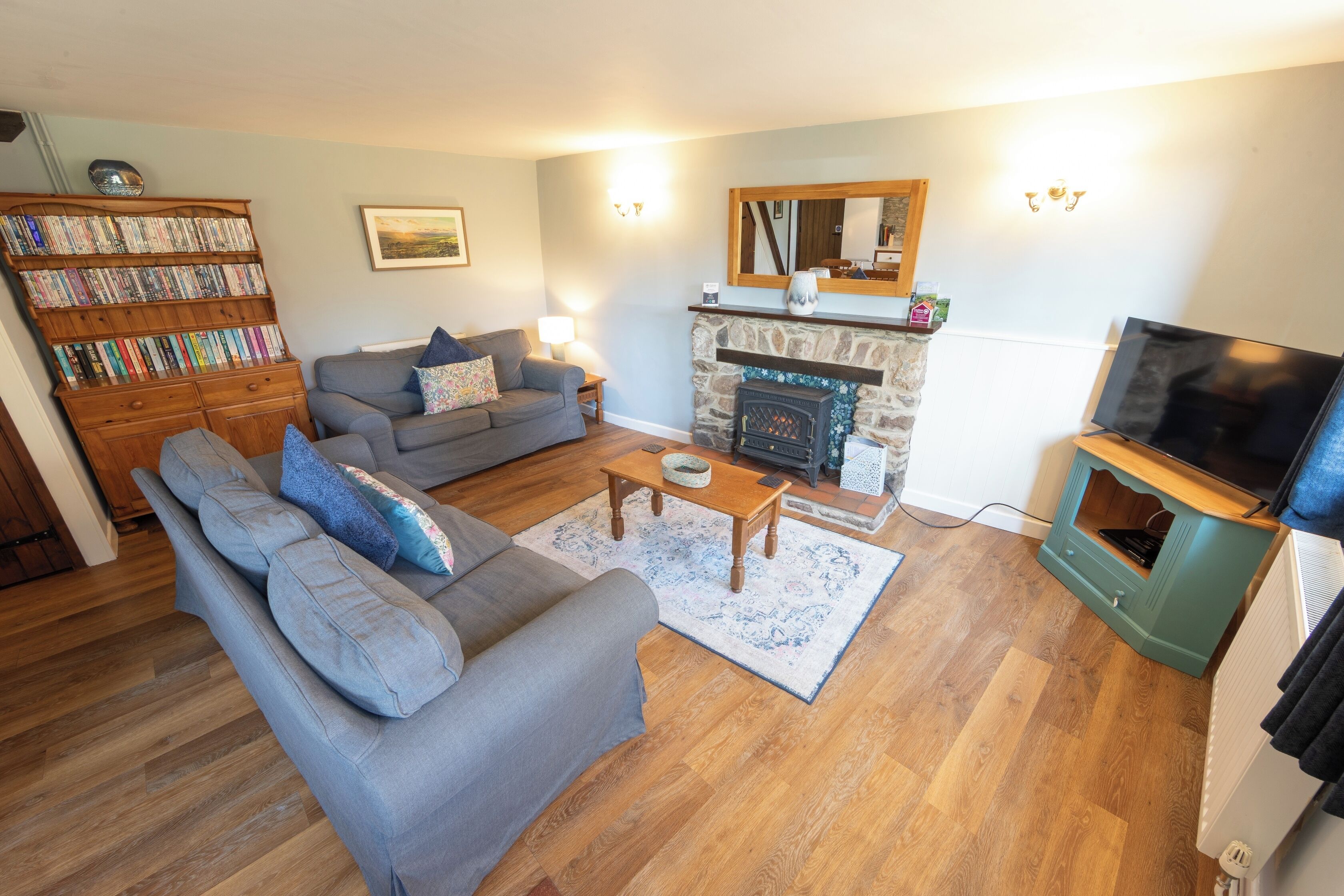 A living room with a sofa, a fireplace, a television, and a bookshelf.