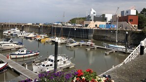 Un port de plaisance avec des bateaux amarrés, une jetée et des bâtiments en arrière-plan.
