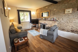 A cozy living room with a stone wall, a fireplace, a television, and a comfortable seating area.