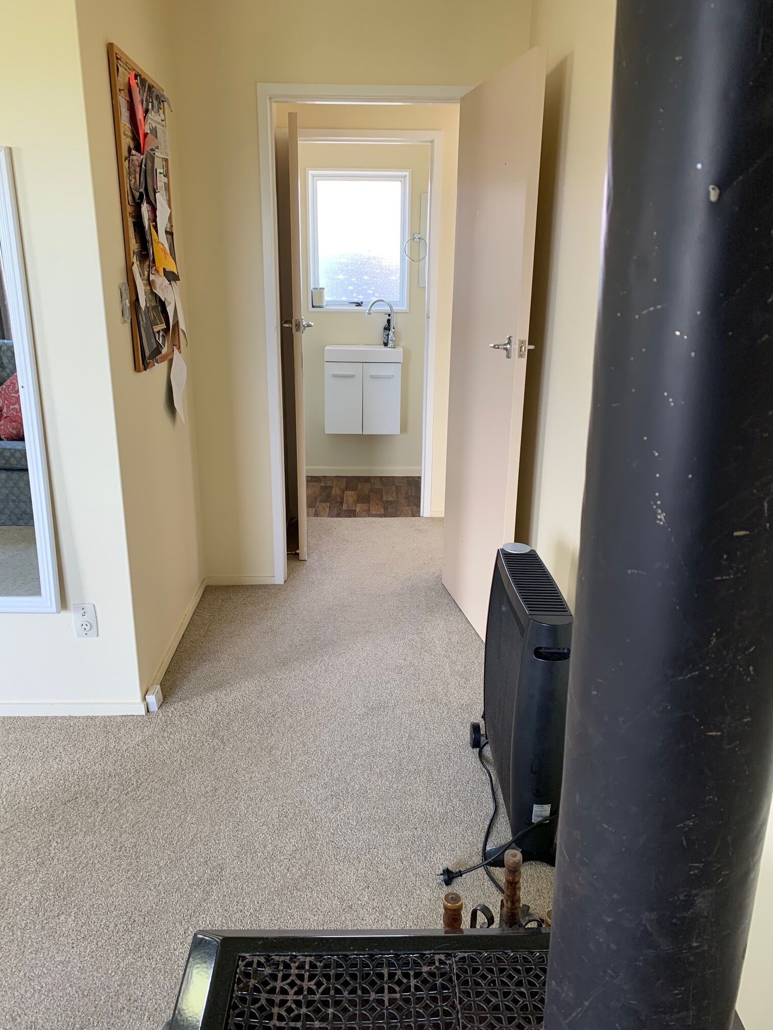 Un couloir menant à une salle de bain équipée d’un lavabo et d’une fenêtre.