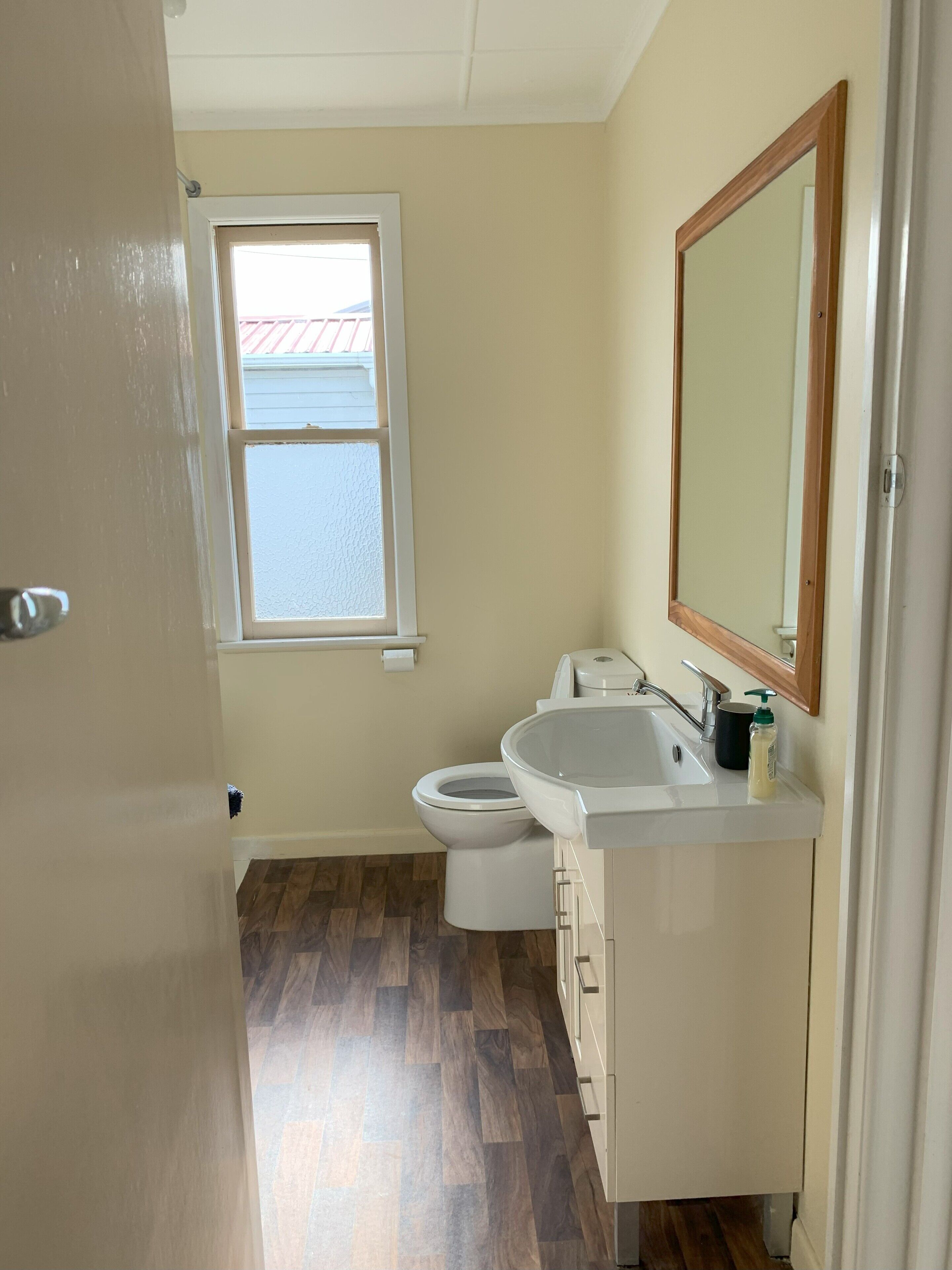 A small bathroom with a toilet, sink, and mirror.