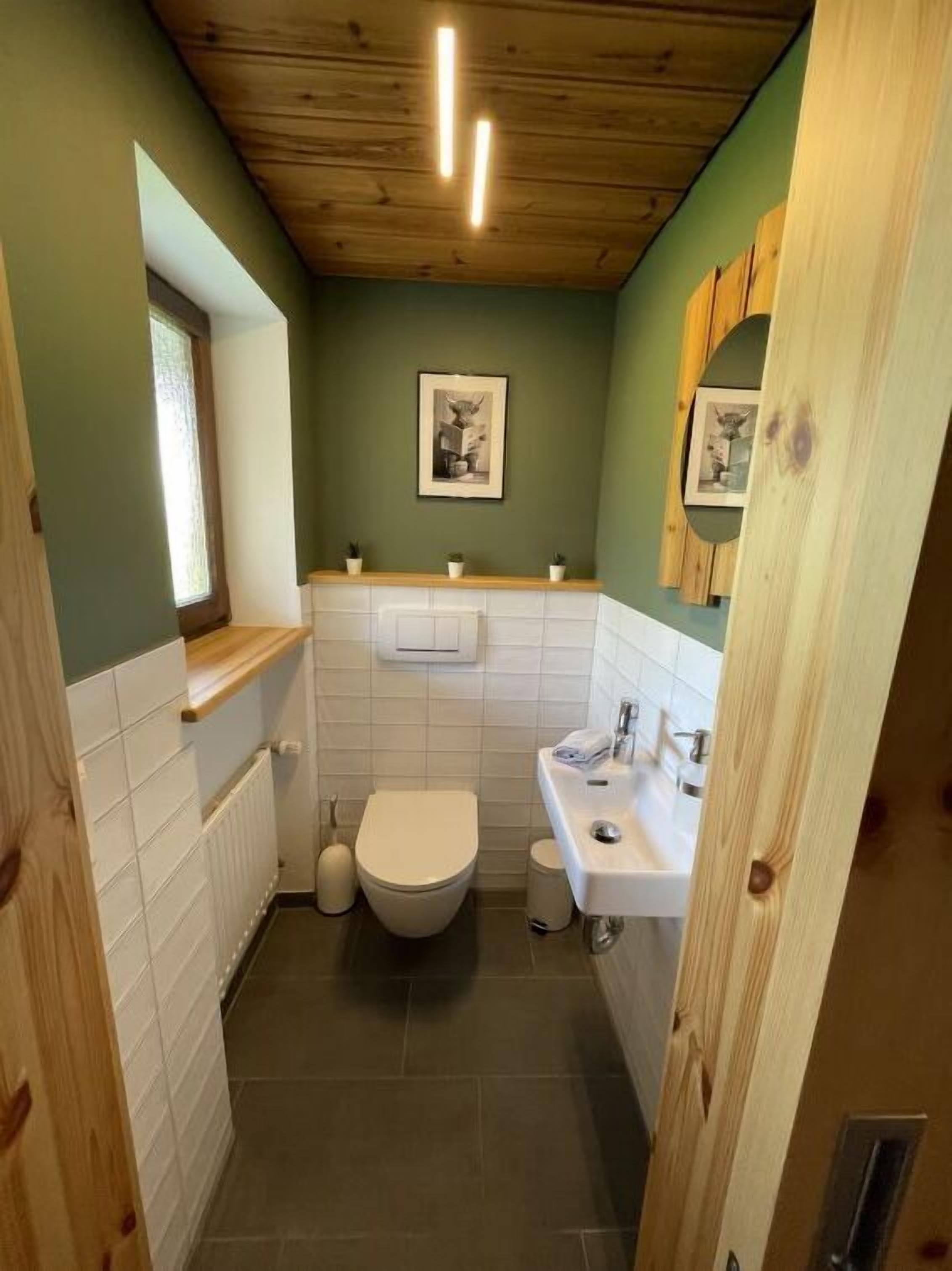 A compact bathroom with a toilet, sink, and a small window.