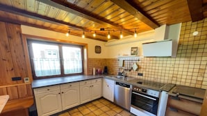 Uma cozinha com armários de madeira, lava-louças, forno e painel de azulejos.