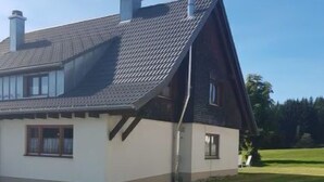 Uma casa com telhado inclinado, chaminé e gramado bem cuidado.
