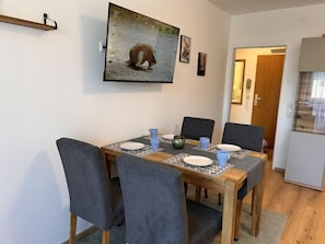 En matplats med ett träbord, fyra grå stolar och en tavla med en räv på väggen.