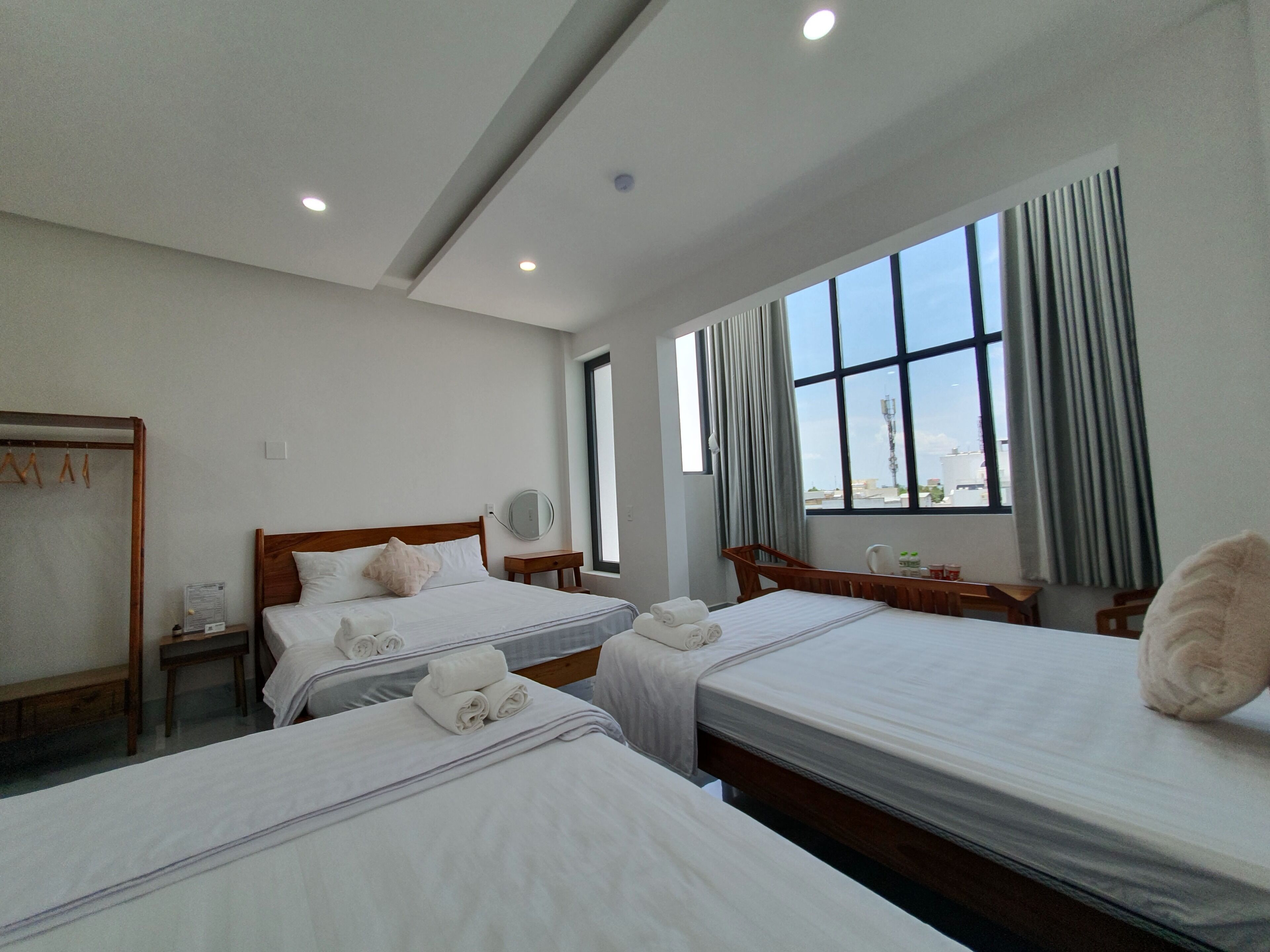 Habitación de hotel con dos camas, un escritorio, una silla, un espejo y un ventanal con cortinas.