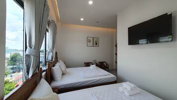Habitación de hotel con dos camas, un televisor montado en la pared y una ventana con cortinas.