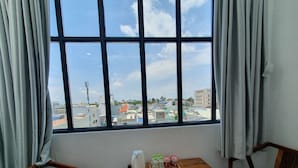 Ein Zimmer mit großem Fenster, zwei Holzstühlen und einem kleinen Holztisch mit Wasserkocher und Flaschenwasser.