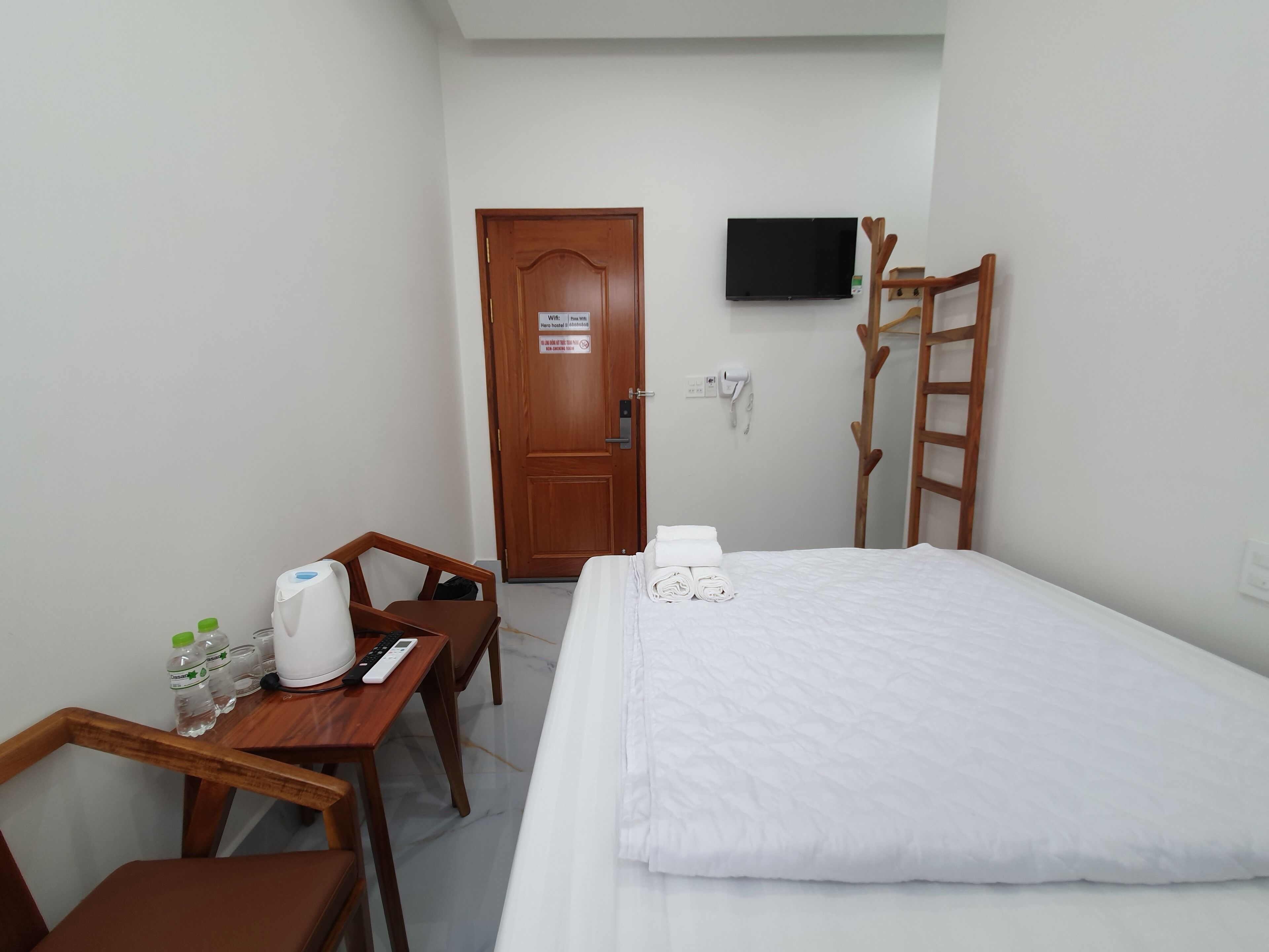 Habitación de hotel con cama, escritorio y silla, televisor montado en la pared y escalera de madera.