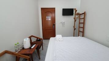 Habitación de hotel con cama, escritorio y silla, televisor montado en la pared y escalera de madera.