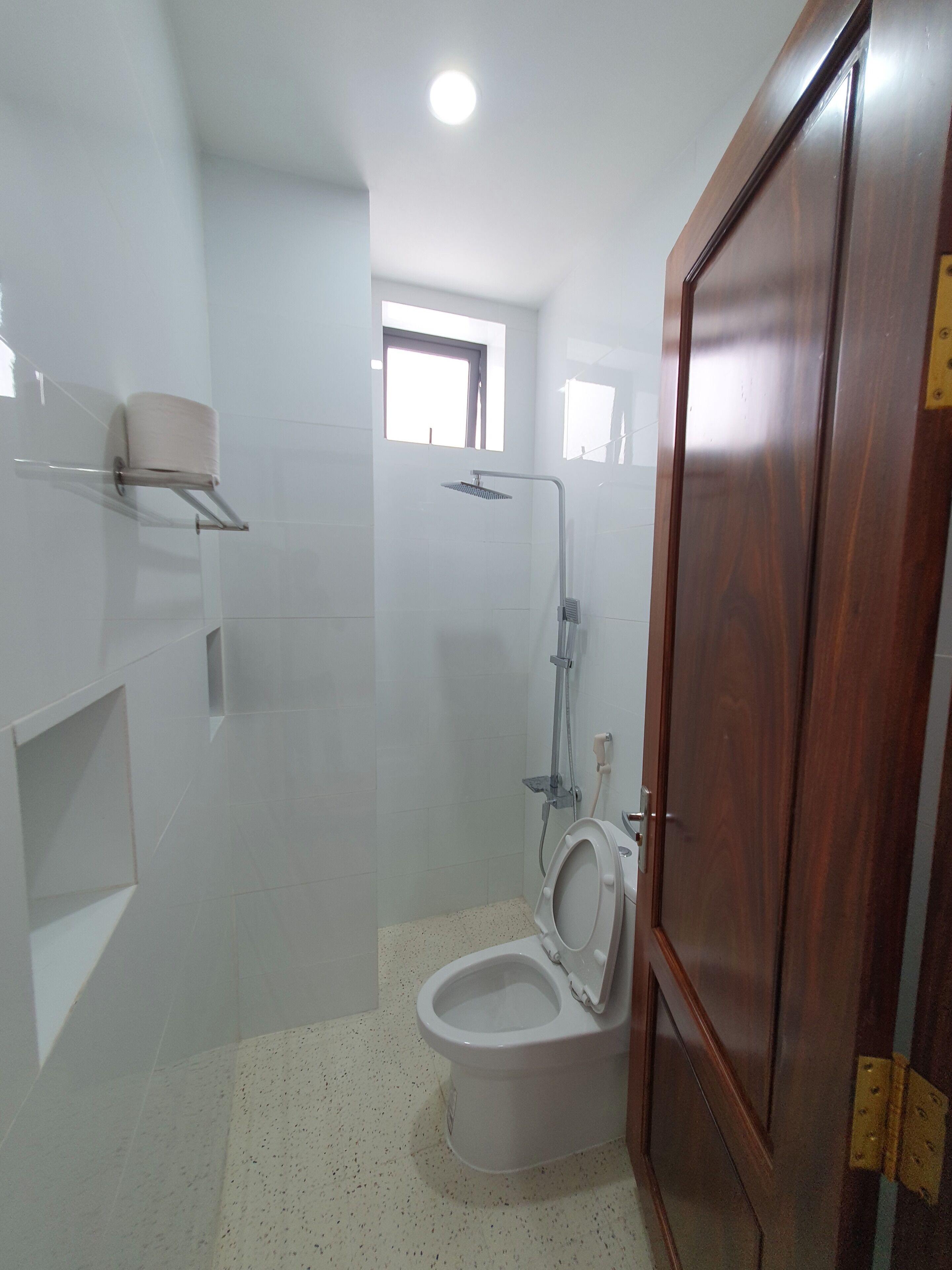 A bathroom with a toilet, a shower, and a small window.