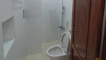 A bathroom with a toilet, a shower, and a small window.