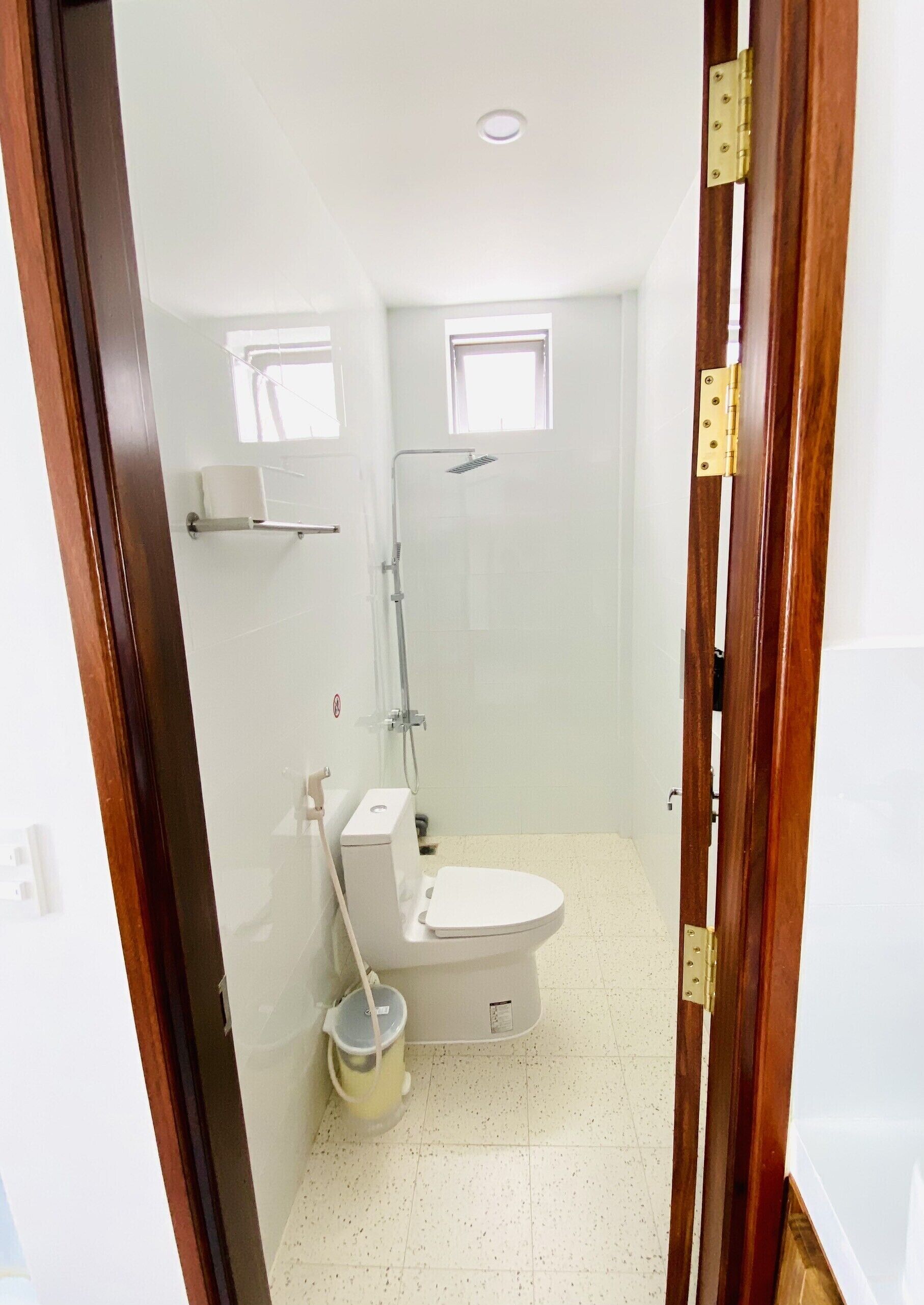 Ein kleines, sauberes Badezimmer mit Toilette, Dusche und einem kleinen Fenster.