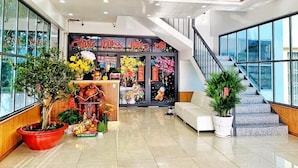 Eine moderne Hotelhalle mit Treppe, einer Rezeption und Topfpflanzen.