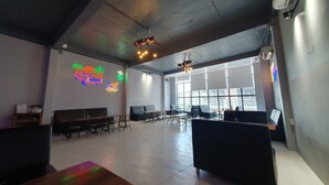 Ein geräumiger Innenbereich mit hoher Decke, großen Fenstern und einer Neonreklame an der Wand.