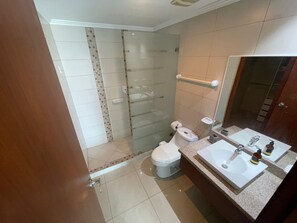 Une salle de bain avec une douche à parois de verre, des toilettes et un lavabo avec un miroir.