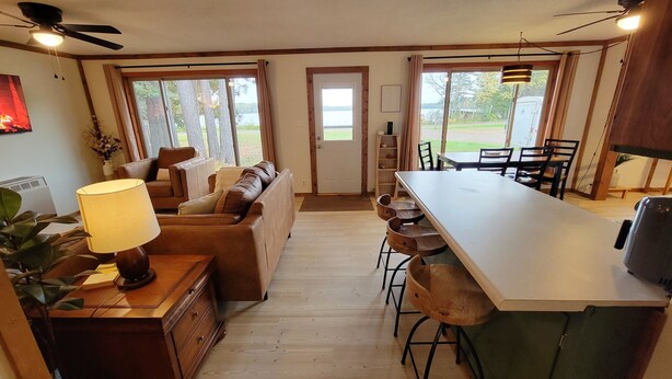 Une cuisine chaleureuse avec un coin repas, des meubles en bois et de grandes fenêtres donnant sur l’extérieur.