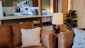 Un salon chaleureux avec un canapé en cuir marron, un coussin à rayures blanches et une lampe de table.