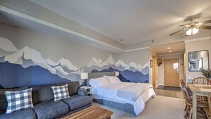 Een slaapkamer met een bed, een bank, een houten salontafel en een eethoek met een tafel en stoelen.