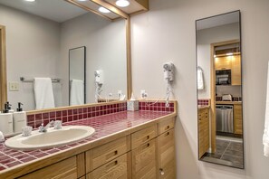 A bathroom with a sink, mirror, hairdryer, and towel rack. - The ultimate ski studio at Keystone!  Upgraded with a premium king size bed. (Keystone)