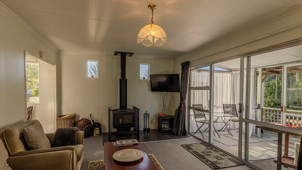Una sala de estar con sofá, una mesa de centro, chimenea, televisor y un amplio ventanal corredera al exterior.