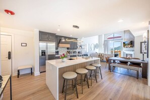 A modern kitchen with a central island, bar stools, and a dining area with a table and chairs.