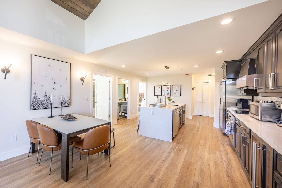 A modern kitchen with a central island, wooden flooring, and stainless steel appliances.