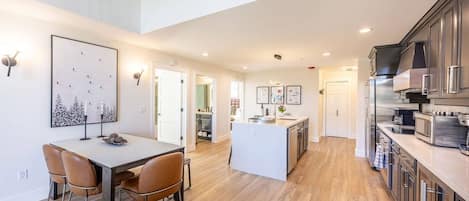 A modern kitchen with a central island, wooden flooring, and stainless steel appliances.