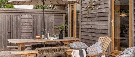 Una terraza de madera con una mesa, sillas y una sombrilla.