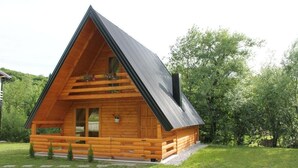 Een houten chalet met een puntig dak, een veranda en een kleine tuin.
