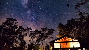 Een sterrenhemel met een huis in de voorgrond, verlicht.