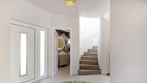 A hallway with a staircase, a round rug, and a door leading to a bathroom. - Casa Ella - Beautifully renovated luxury townhouse walking distance of Carvoeiro (Carvoeiro)