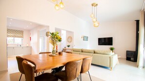 A modern living room with a sofa, a dining table with chairs, a TV, and a fireplace. - Casa Ella - Beautifully renovated luxury townhouse walking distance of Carvoeiro (Carvoeiro)